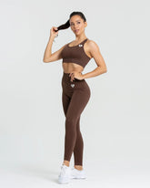 امرأة ترتدي سروالًا ضيقًا من نوع BEST Power Seamless للنساء من حمالة صدر رياضية باللون البني الجوزي وبنطلون ليقنز.